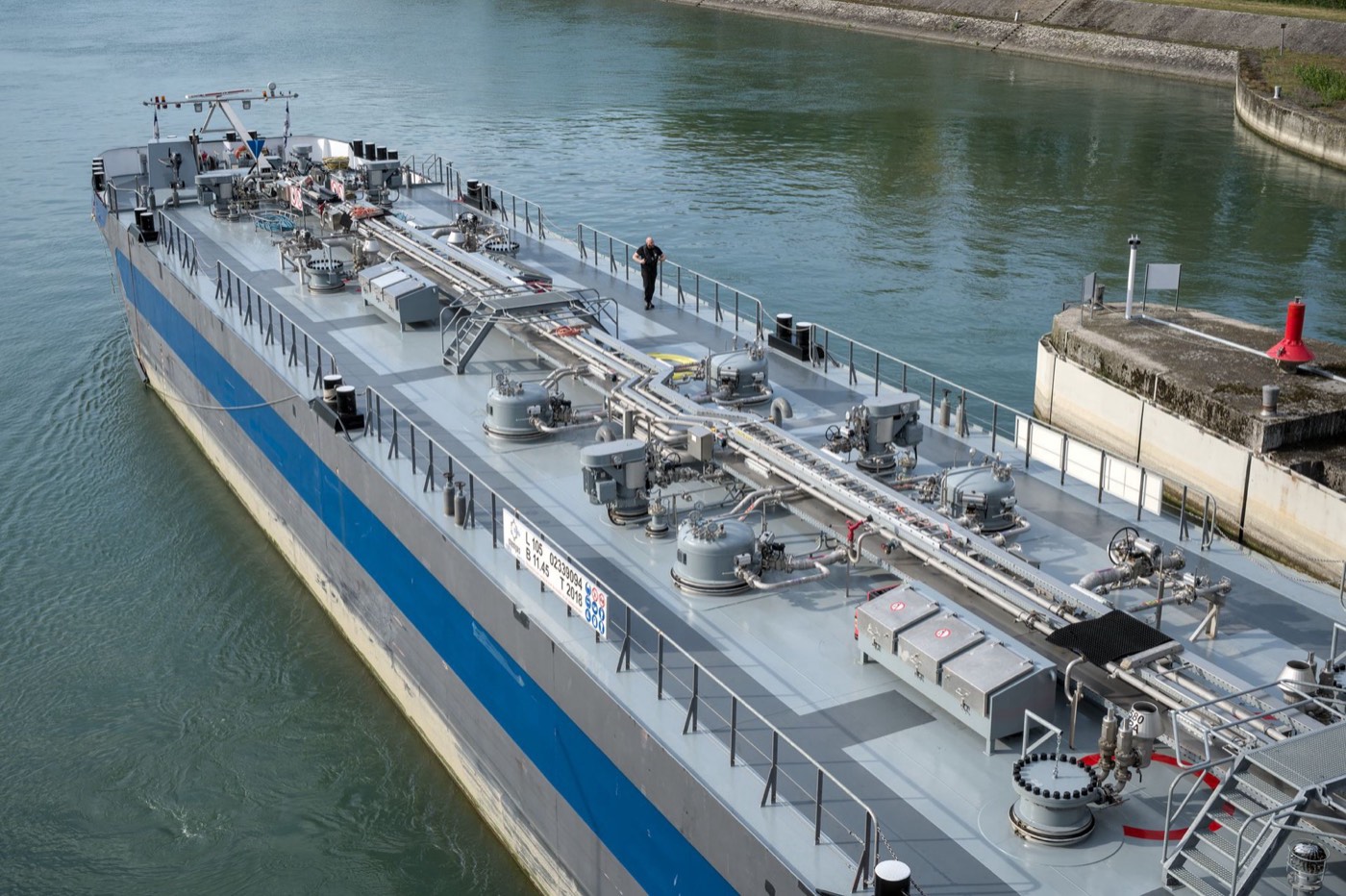 Crew on the deck of a bunker barge, manifold and cargo lines in view