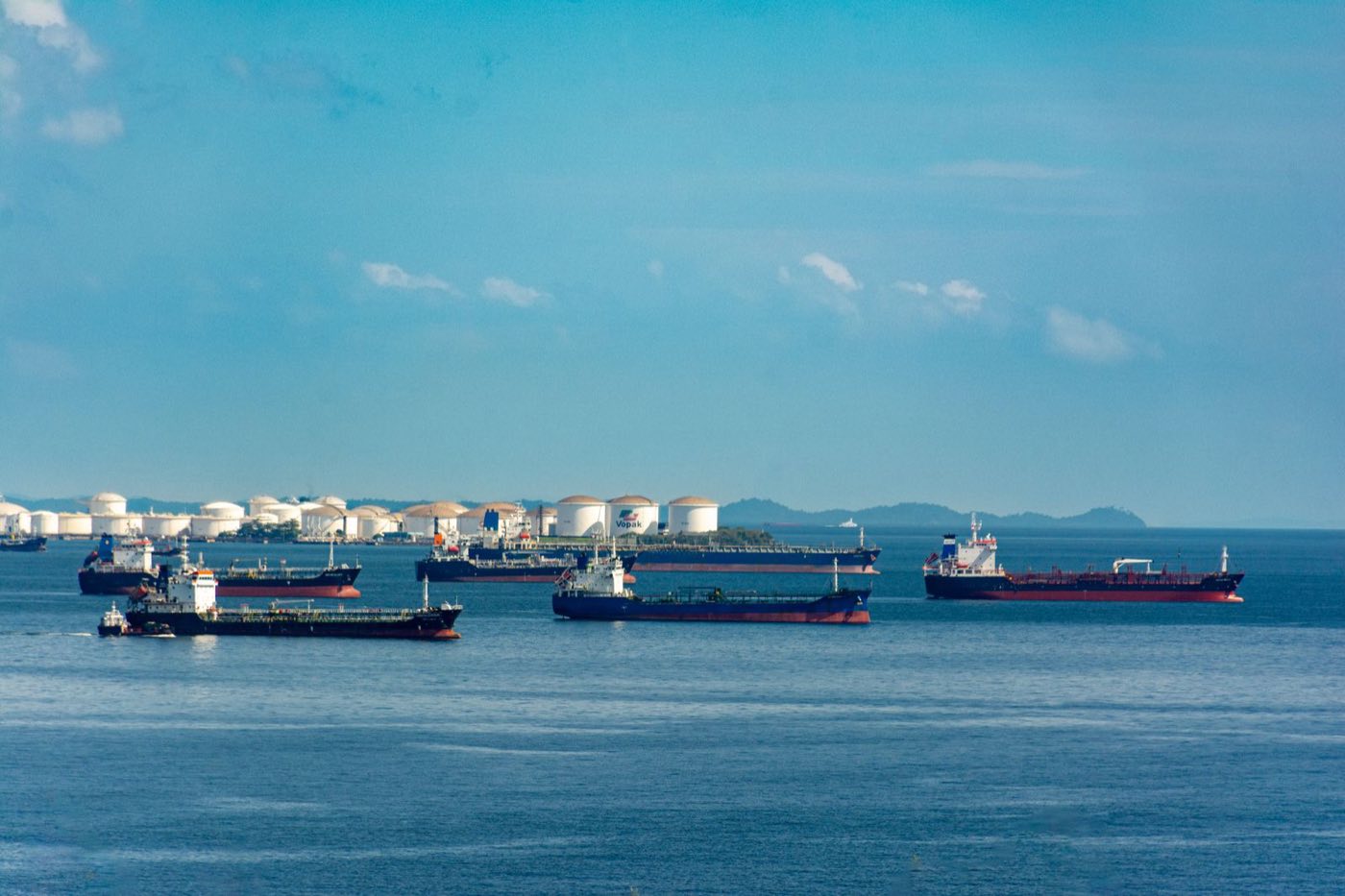 Vessels anchored off a coastal terminal with storage tanks